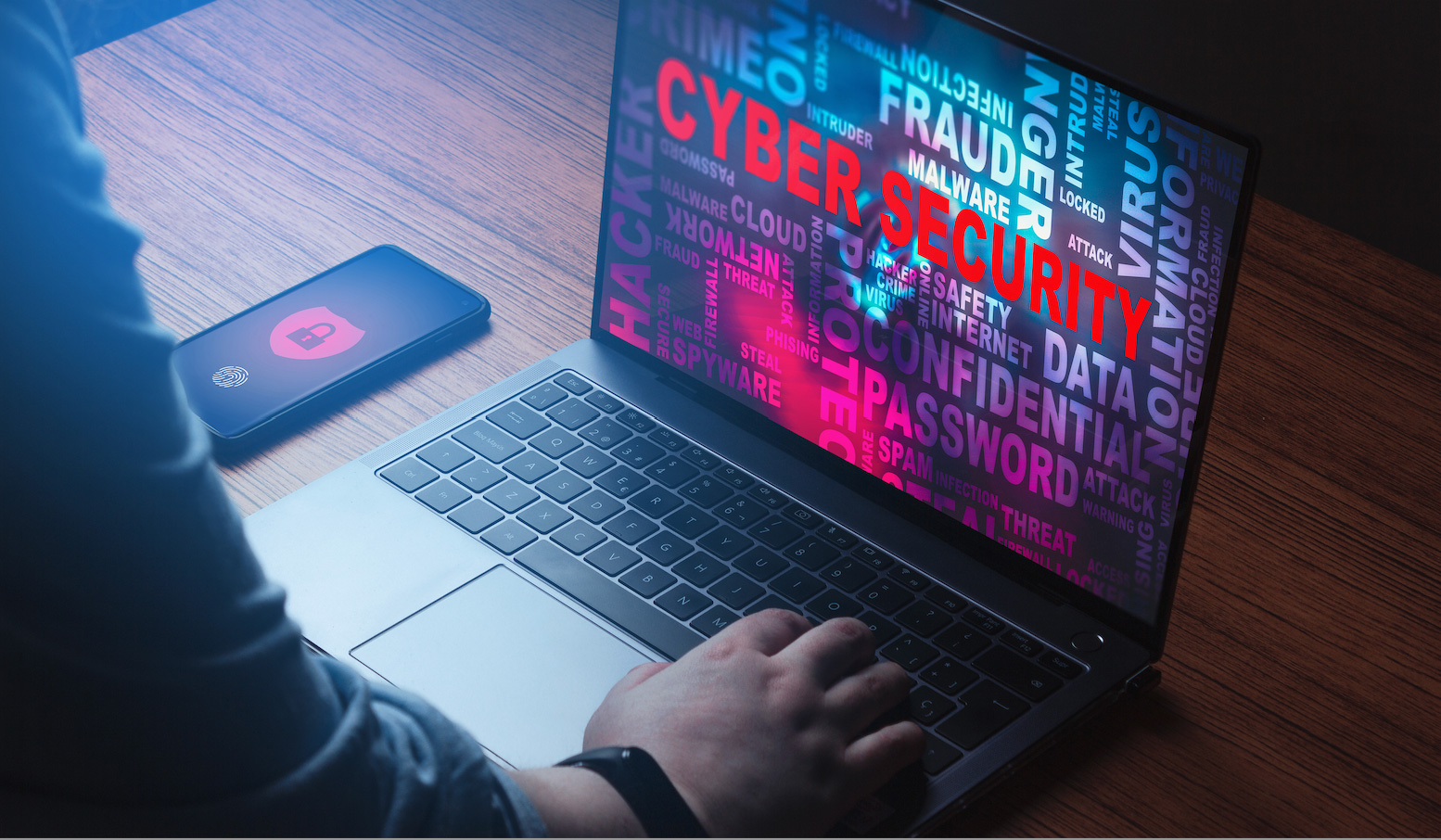Laptop displaying cybersecurity word cloud next to secured smartphone